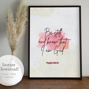Puede incluir: Una impresión de arte de pared imprimible con un fondo de acuarela en tonos de rosa y amarillo. La impresión presenta el texto "Estate quieto y sabe que yo soy Dios." con la referencia bíblica "Salmo 46:10" debajo.