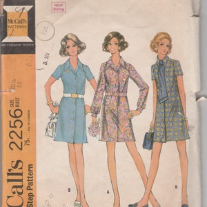 May include: Vintage McCall's sewing pattern 2256 for women's dresses. The pattern features illustrations of three dress styles with button-up fronts, belts, and a scarf option. The pattern includes sizing information and the text "Step-by-Step Pattern".