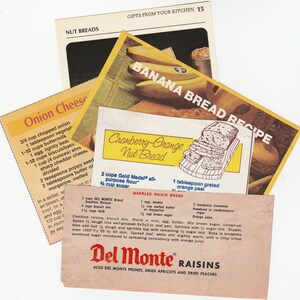 May include: A collection of vintage recipe cards for nut breads, including banana bread, cranberry-orange nut bread, and marbled raisin bread. The cards feature handwritten text and illustrations, with a Del Monte Raisins advertisement.