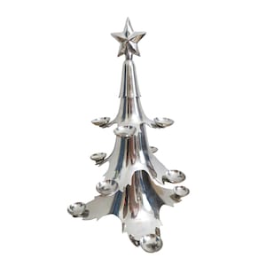 May include: A silver-colored Christmas tree-shaped candle holder. The tree has multiple small, round candle holders and is topped with a star. The tree is made of metal and has a reflective surface.