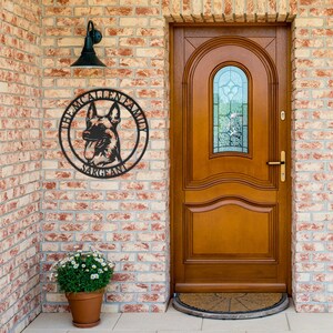 May include: A circular black metal wall sign featuring a silhouette of a German Shepherd dog in the center. The text THE MCALLEN FAMILY is arched along the top edge, and the word SARGEANT is printed along the bottom edge of the circular frame.