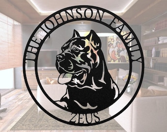 Può includere: Un'insegna da parete circolare in metallo nero con la sagoma di un cane Cane Corso al centro. Il testo THE JOHNSON FAMILY è arcuato lungo il bordo interno superiore e il nome ZEUS è centrato lungo il bordo interno inferiore della cornice.