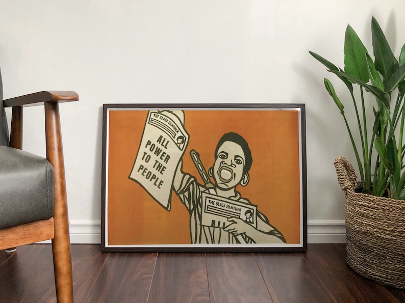 May include: A framed poster with an orange background featuring a young Black man holding a newspaper that reads "The Black Panther" and "All Power to the People".