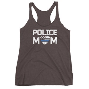 May include: A dark charcoal gray racerback tank top featuring the white text POLICE MOM printed on the front. The letter O in MOM is replaced by a heart shape containing a white and blue striped flag design with white stars on a blue field.
