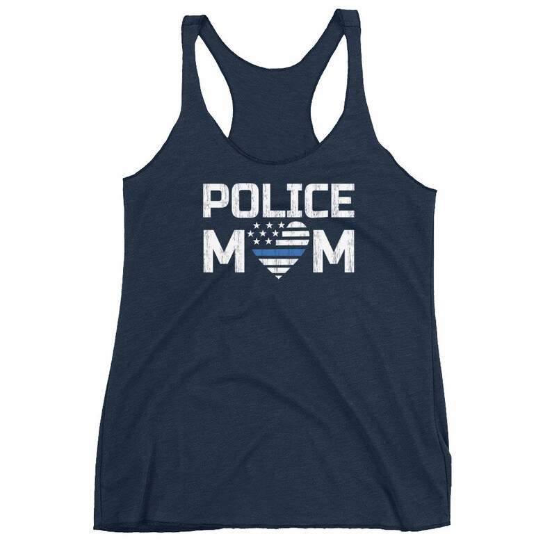 May include: A navy blue racerback tank top featuring the white distressed text POLICE MOM, with the letter O replaced by a heart shape containing a white star-spangled pattern and a single horizontal blue line across the center of the heart.