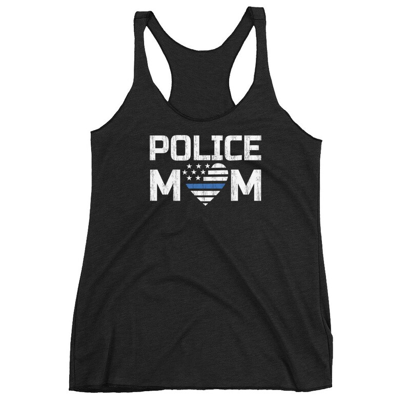 May include: A black racerback tank top featuring the white text POLICE MOM with a heart-shaped American flag graphic in the center. The heart design includes white stars and stripes with a single horizontal blue line across the middle of the heart.