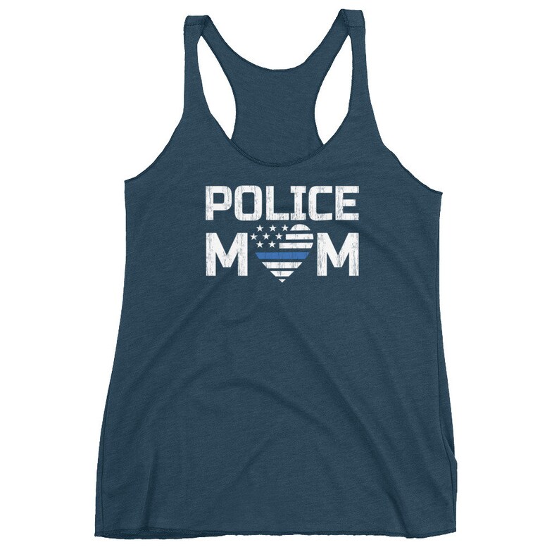 May include: A dark blue racerback tank top featuring the white text POLICE MOM, with the letter O replaced by a heart graphic containing a white star field and a thin horizontal blue line across the center of the heart design.