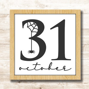 Puede incluir: Una impresi&oacute;n enmarcada con texto negro que dice "31 de octubre" con un dise&ntilde;o de ara&ntilde;a y telara&ntilde;a incorporado en el n&uacute;mero 3.