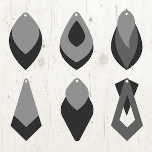 Könnte beinhalten: Sechs Paar übereinanderliegende Papierschmuckohrringe in verschiedenen Formen, darunter Tropfen, Diamant und Blatt. Die Ohrringe sind in Grautönen und Schwarz.