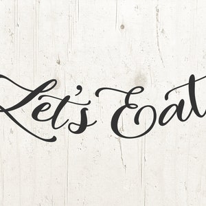 May include: Let's Eat written in black cursive script on a white wood background.