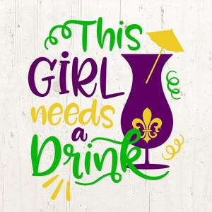 Może przedstawiać: Zielony i fioletowy tekst na białym drewnianym tle brzmi "This Girl Needs a Drink". Obok tekstu znajduje się fioletowy kieliszek do koktajlu z żółtym parasolem i złotym wzorem lilii.