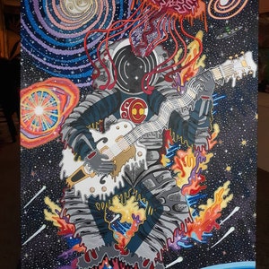 May include: A psychedelic painting of an astronaut playing a white electric guitar in space. The astronaut is surrounded by swirling galaxies, stars, and a red, dripping jellyfish. The guitar is dripping with gold paint.