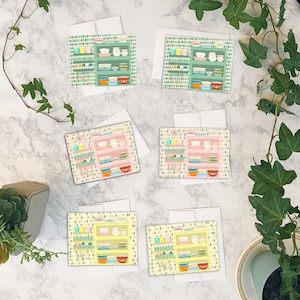 May include: Set of six greeting cards featuring a vintage kitchen design with colorful bowls and plates on shelves. Each card has a different color background and a different arrangement of bowls and plates.