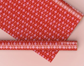 May include: Two rolls of red wrapping paper with a pink star pattern. The paper is rolled up and the ends are visible.