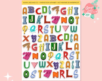 May include: A sheet of colourful vintage sign alphabet stickers. The letters are in various colours and styles, with a white outline and a black shadow. The letters are arranged in alphabetical order.