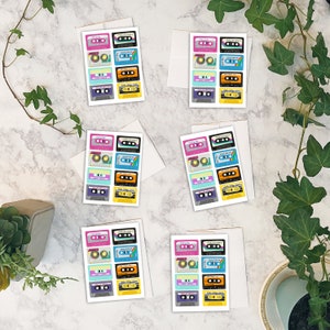 May include: Eight cards with a colorful cassette tape design. Each card has nine different cassette tapes with various colors and patterns. The text on the cards reads "Just a Mix Tape" and "Mix Tape Songs".
