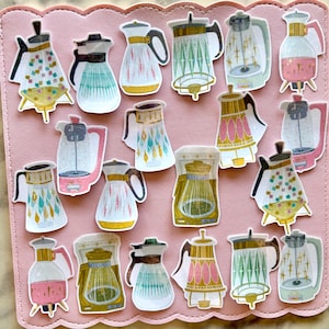 May include: A collection of colorful, retro-style coffee pot stickers. The stickers feature various designs with pastel colors, gold accents, and geometric patterns. The stickers are arranged on a pink surface.