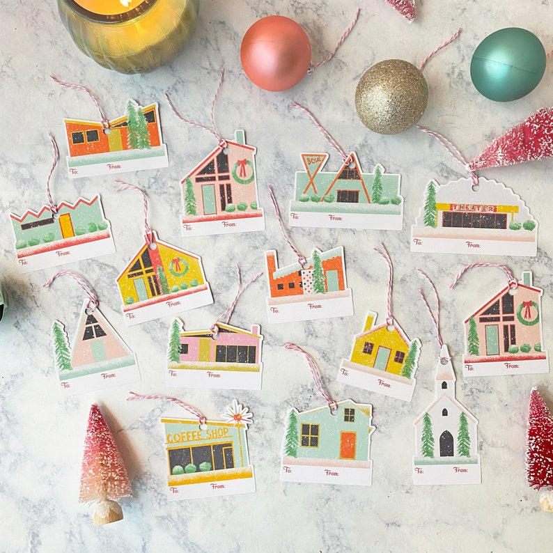 Puede incluir: Un conjunto de 14 etiquetas de regalo coloridas con ilustraciones de casas de estilo moderno de mediados de siglo, una cafeter&iacute;a, un teatro y una iglesia. Cada etiqueta tiene un espacio en blanco para escribir "Para" y "De".