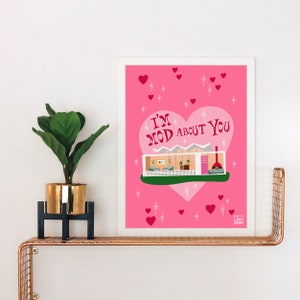 May include: A pink and white print with a heart-shaped design featuring a mid-century modern house. The text "I'm Mod About You" is inside the heart.