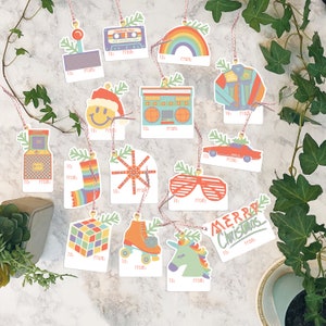 May include: Set of 12 retro-themed Christmas gift tags with various designs, including a cassette tape, rainbow, roller skates, a unicorn, a boombox, a smiley face, sunglasses, a car, a snowflake, a video game, a stocking, and a Merry Christmas tag.