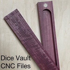 Può includere: Una scatola di legno con un coperchio incernierato, realizzata in legno di cuore viola. La scatola è aperta, rivelando un interno vuoto. Il testo "Dice Vault CNC Files" è visibile sotto la scatola.