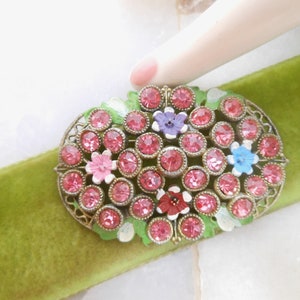 May include: A vintage brooch with a cluster of pink, blue, and white enamel flowers surrounded by clear rhinestones in a gold tone setting.