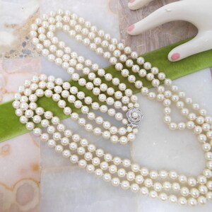 May include: A four-strand pearl necklace with a silver clasp in the shape of a flower.