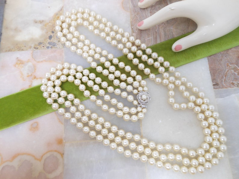 May include: A four-strand pearl necklace with a silver clasp in the shape of a flower.