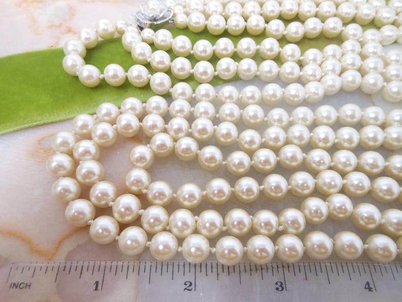 May include: A multi-strand pearl necklace with a silver clasp. The necklace is approximately 4 inches long.