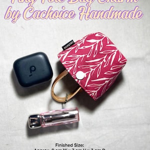 May include: A tiny tote bag charm in magenta fabric with a white leaf pattern, featuring a white snap closure, tan leather handles, and a black tag reading "cachoice". Text reads: "Tiny Tote Bag Charm by Cachoice Handmade" and "Finished Size: Approx. 8 cm W x 7 cm H x 3 cm D" and "Approx. 10 cm W x 9 cm H x 4 cm D".