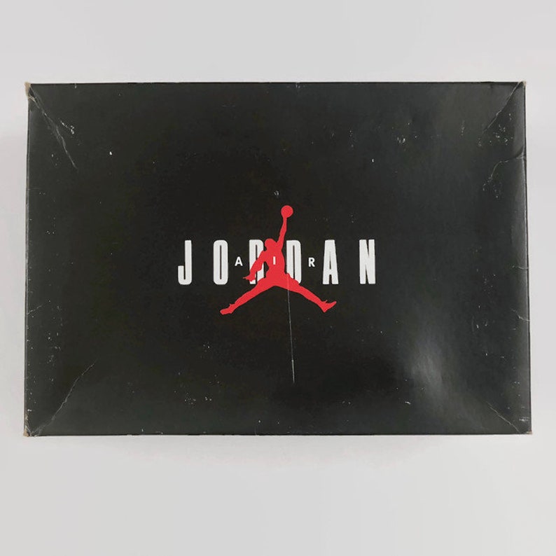 May include: A black shoebox with the word "JORDAN" in white letters and a red silhouette of a basketball player with the word "AIR" in white letters above the player.