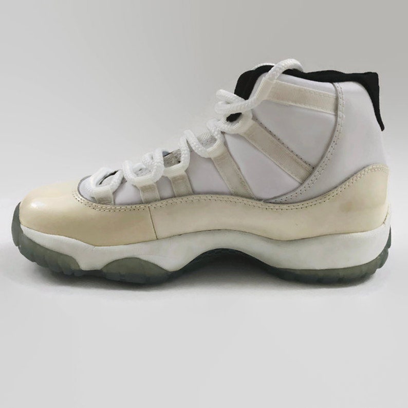 May include: White leather high-top sneakers with a white and black lace-up closure. The sneakers have a white midsole and a translucent outsole.