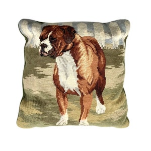 May include: Square decorative pillow featuring a detailed needlepoint design of a Boxer dog. The dog is depicted in shades of brown, white, and tan, set against a backdrop of green and blue hues. The pillow has a green border.