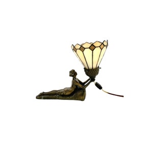 May include: A bronze sculpture of a woman holding up a Tiffany-style stained glass lampshade. The lampshade is white with brown accents and has a geometric pattern.