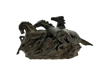 May include: A bronze sculpture of three horses running, with a textured rocky base.