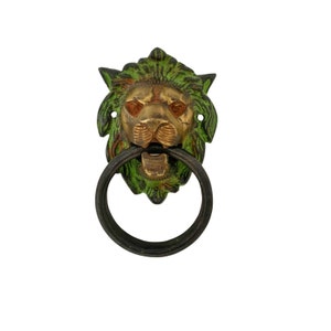 May include: A green and gold lion head door knocker with a black metal ring.