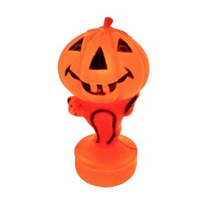May include: A bright orange plastic jack-o'-lantern figure standing on a circular base. The pumpkin head features triangular eyes, a triangular nose, and a wide, toothy grin with black painted details. The figure has small arms extended outward.