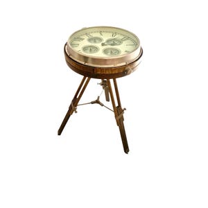 May include: A wooden table with a round top featuring a clock face with Roman numerals and four smaller compass dials. The table is supported by a tripod base made of wood.