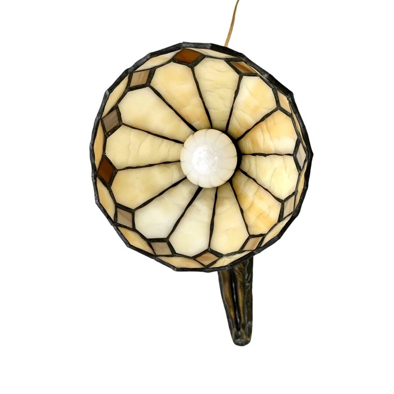May include: A stained glass lamp with a brown and beige geometric pattern. The lamp has a round shade and a curved metal base.