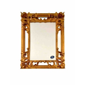 May include: A gold-colored ornate mirror with a rectangular frame. The frame has a detailed, carved design with a raised edge. The mirror has a sticker that says "Made in Italy".