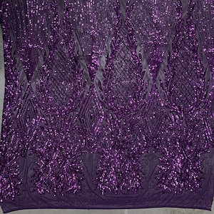 May include: Purple sequined fabric featuring a geometric design and floral accents. The sequins are iridescent, creating a shimmering effect.