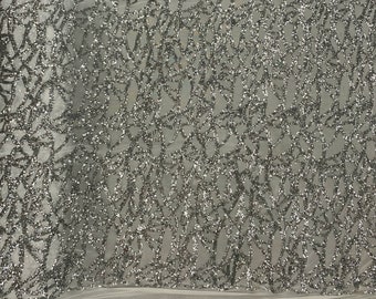 May include: Silver glitter fabric with a geometric pattern. The fabric has a mesh backing.