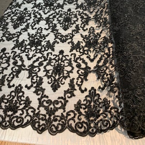 May include: Black beaded lace fabric with a damask pattern. The lace is on a white mesh background.