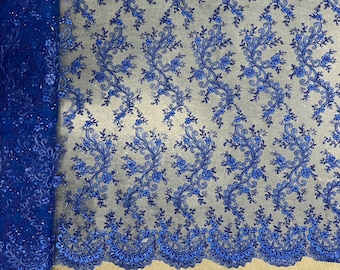 Puede incluir: Tela de encaje bordada azul real con un patrón floral. El encaje tiene un borde festoneado.