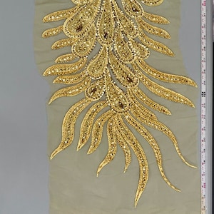 May include: Gold sequined peacock feather trim applique for clothing or crafts. The trim is approximately 18 inches long and features a delicate mesh backing.