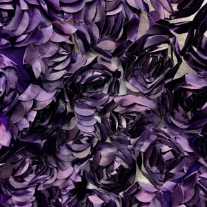 May include: Purple fabric with a 3D floral design. The fabric is made of a soft, textured material and features a repeating pattern of raised flowers.