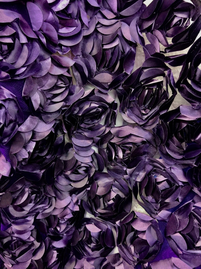 May include: Purple fabric with a 3D floral design. The fabric is made of a soft, textured material and features a repeating pattern of raised flowers.