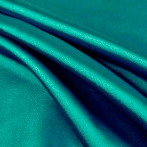 May include: A smooth, teal fabric with a silky texture. The fabric is folded and draped, creating soft folds and curves.
