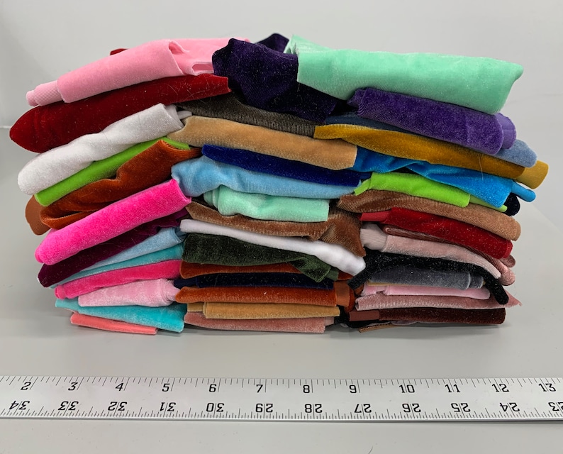 K&ouml;nnte beinhalten: Ein Stapel von 20 verschiedenen farbigen Samtstoffproben. Die Proben sind in einem Stapel angeordnet, wobei die oberste Probe eine hellgr&uuml;ne Farbe hat. Die Proben sind alle in verschiedenen Gr&ouml;&szlig;en und Formen.