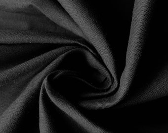 May include: Close-up of a black fabric with a textured surface. The fabric is folded and draped, creating a soft, flowing look.